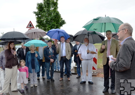 Zeremonie vor aufgespannten Regenschirmen: Mechernichs Bürgermeister Dr. Hans-Peter Schick bat um Verständnis, dass er bei seiner Ansprache keinen Schirm über dem Kopf wünsche: „Als Landwirt bin ich im Augenblick für jeden Tropfen dankbar, der von oben kommt.“ Als Landrat Günter Rosenke, hier noch mit aufgespanntem Schirm, mit seiner Rede dran war, tat er es dem Bürgermeister gleich: „Auch der Landrat freut sich, dass es endlich regnet!“ Foto: Manfred Lang/pp/Agentur ProfiPress
