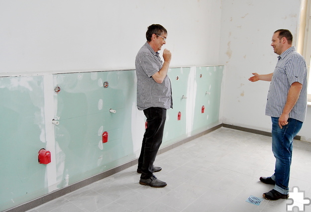 Bauleiter David Esch (r.) und Hans-Peter Siebum, Teamleiter Gebäudemanagement, begutachten die Anschlüsse für die Gemeinschaftswaschmaschinen. Foto: Renate Hotse/pp/Agentur ProfiPress