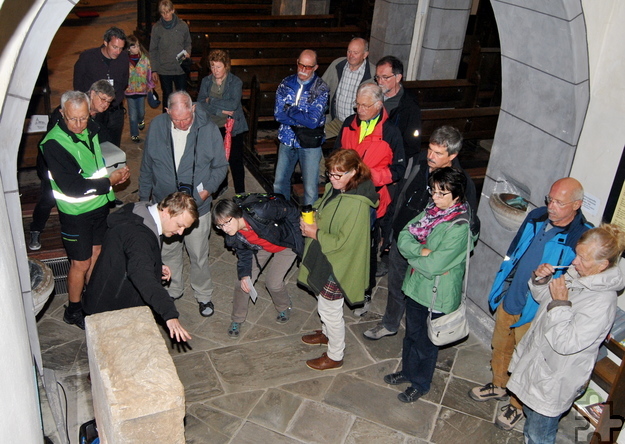 LVR-Mitarbeiter Eugen Rung (l.) erklärt den Besuchern in der Weyerer Pfarrkirche die Inschrift des Matronensteins. Foto: Renate Hotse/pp/Agentur ProfiPress