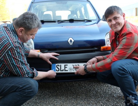 Werner Keutgen (links) und Christian Gehlen montierten Karfreitag das Kennzeichen an den Wagen, den sie anschließend an die Familie übergaben. Foto: Reiner Züll/pp/Agentur ProfiPress
